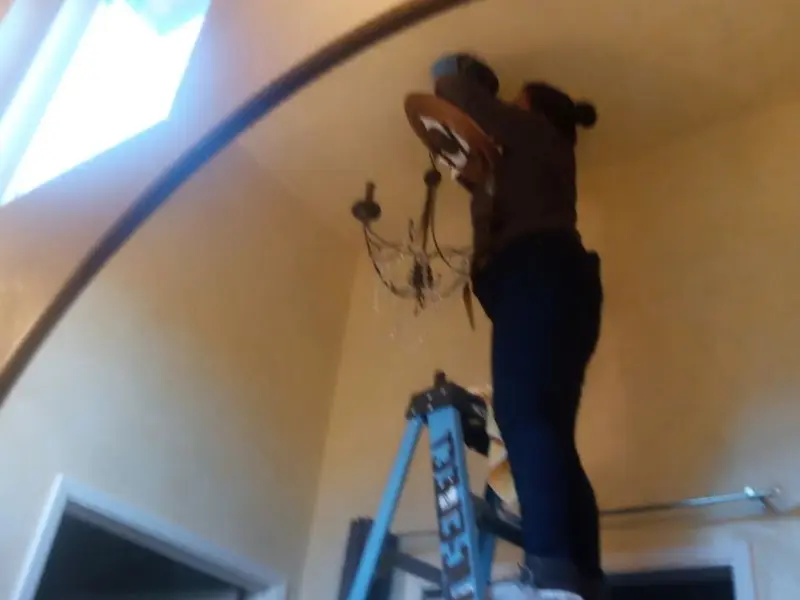 Electrician installing a chandelier in a Elkin residence